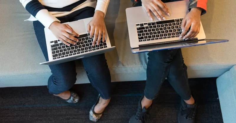 Two people working on laptops from above, showcasing collaboration in a tech environment.