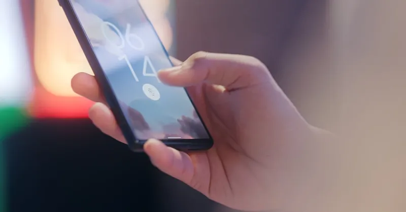 Close-up of a hand holding a smartphone locked with a fingerprint sensor.